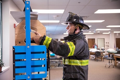Male wearing firefighter uniform while performing occupational therapy exercise