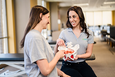 Therapist showing a patient a model of the pelvic bowl.