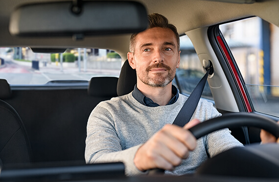 A man in the driver seat of his car looking into his rearview mirror